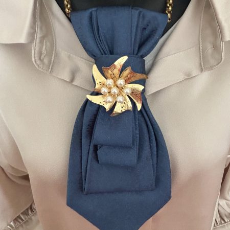 Handmade, elegant blue necktie accessory adorned by a beautiful golden flower brooch.
