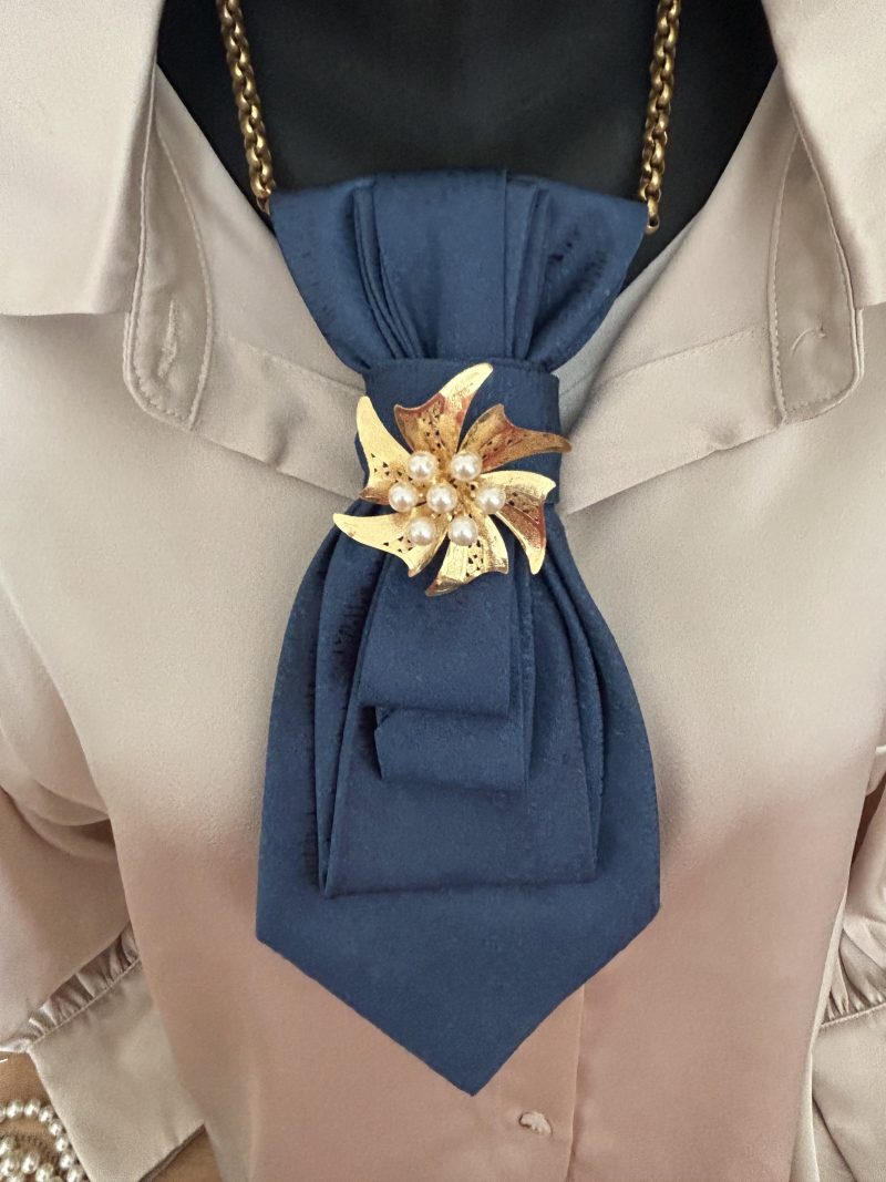 Handmade, elegant blue necktie accessory adorned by a beautiful golden flower brooch.