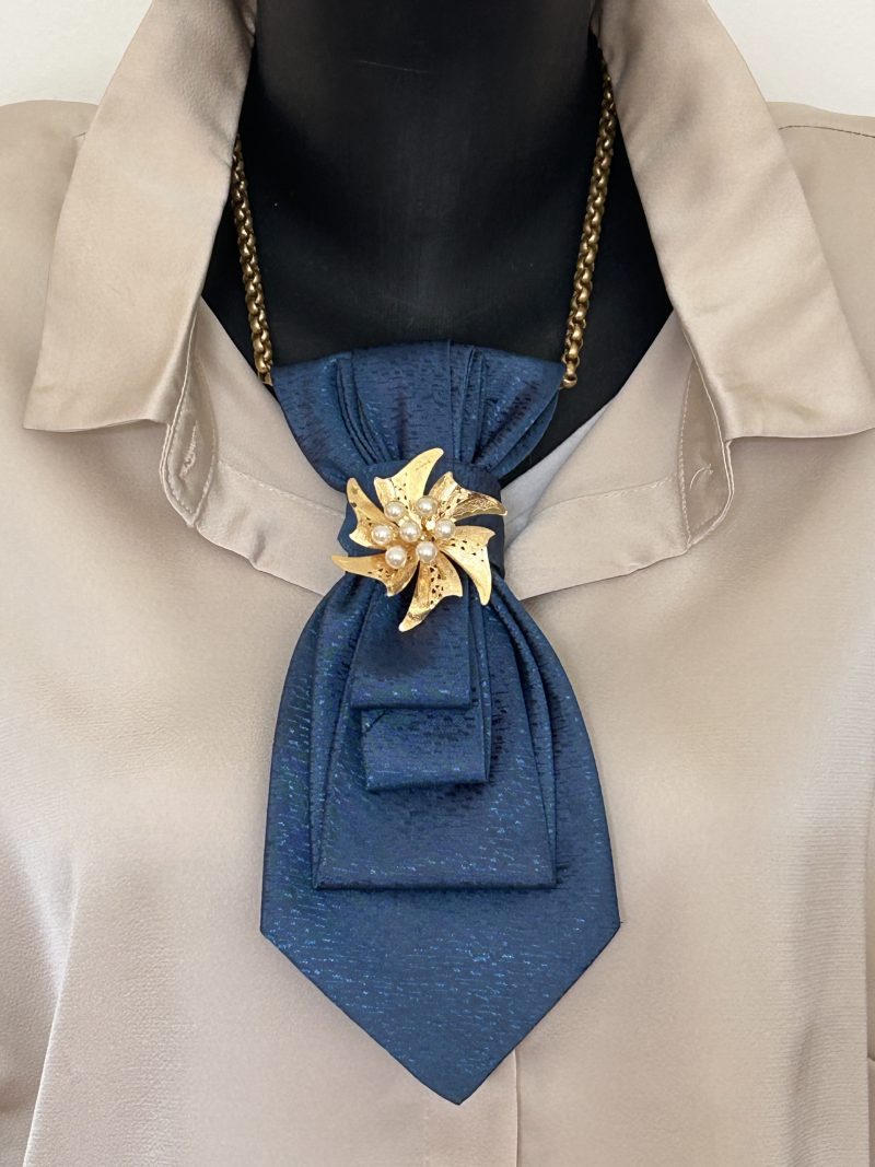 Handmade, elegant blue necktie accessory adorned by a beautiful golden flower brooch.