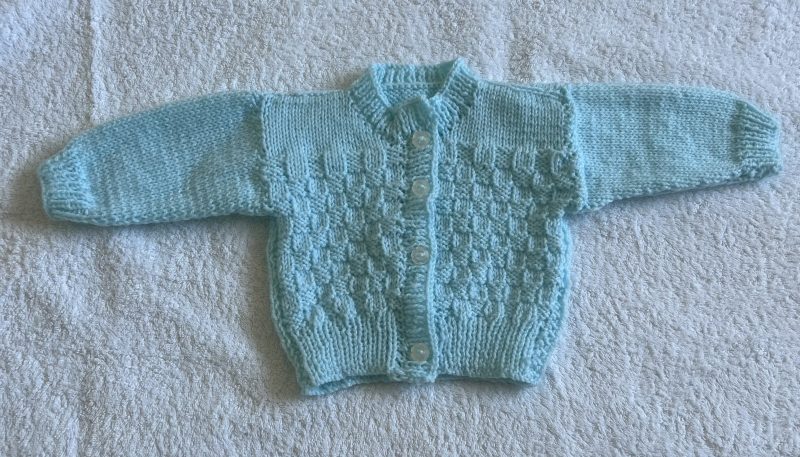 Hand knitted blue baby cardigan .