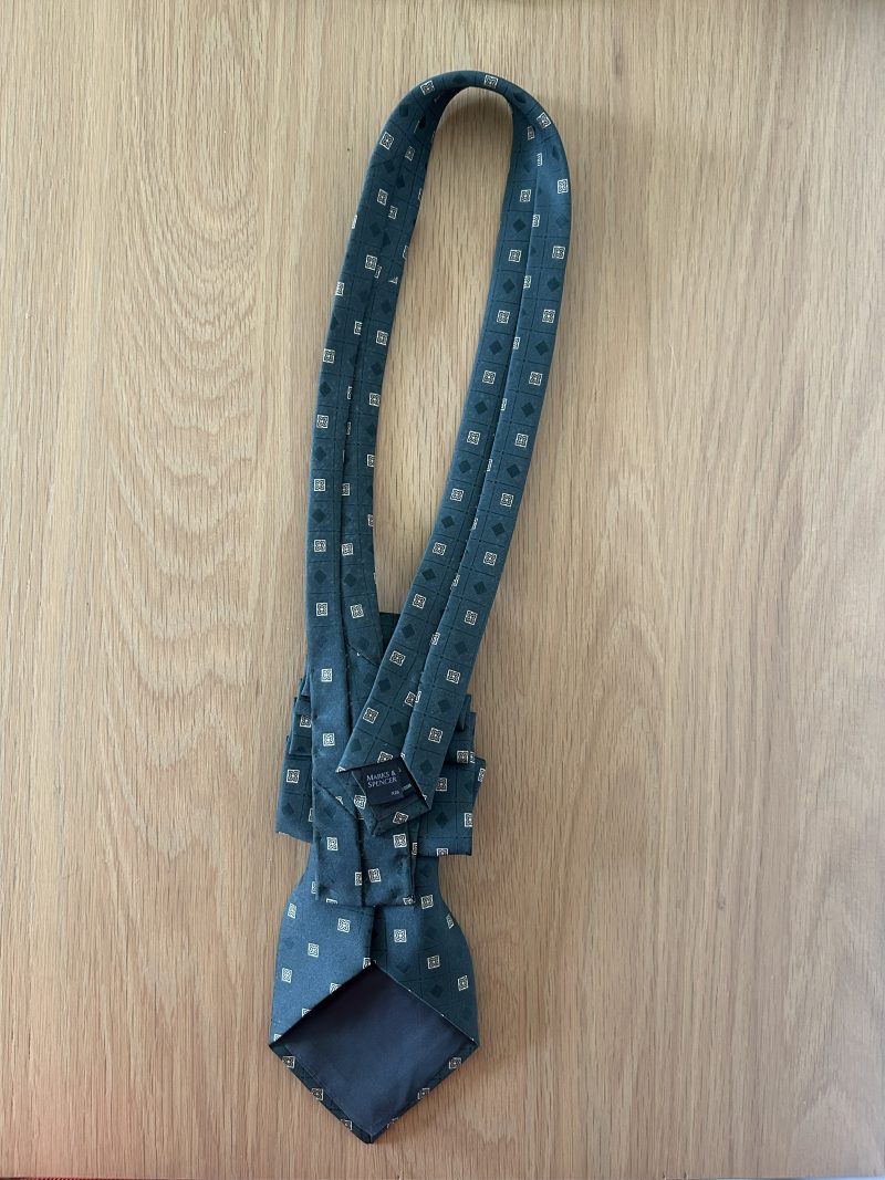 Pendant Elegant dark green patterned silk tie accessory adorned with a golden brooch