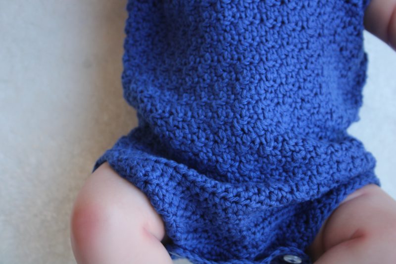 View of the textured stitch around the middle of the blue cotton baby romper