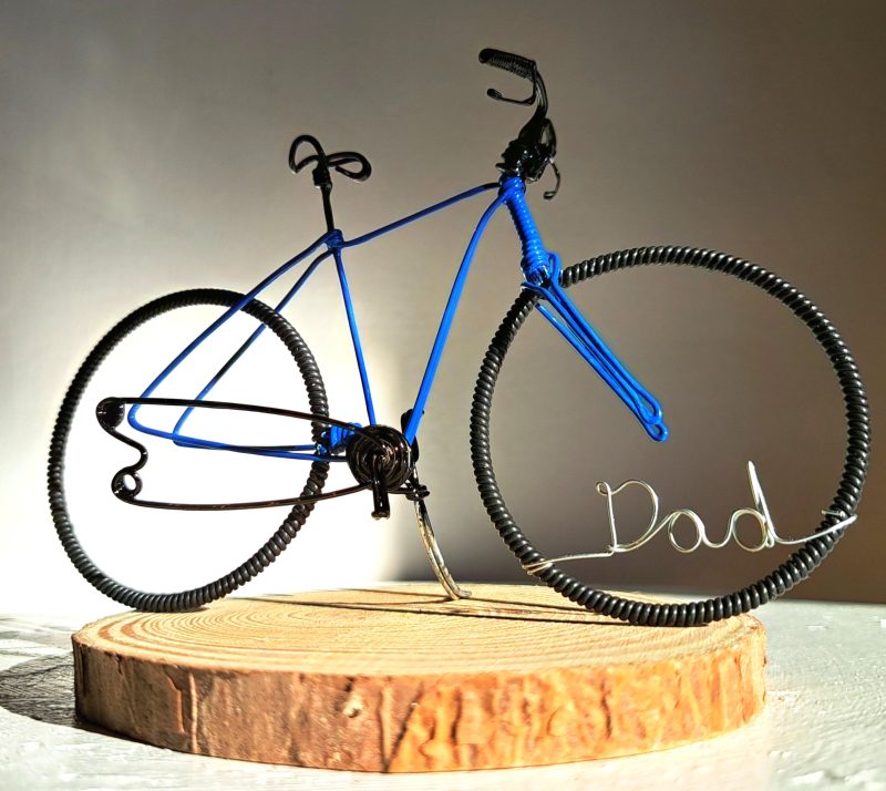 Handmade, blue colour, road style wire bicycle sculpture. Approximately 9cm long 4.5cm high, personalised with a name written in wire and set into the front wheel.