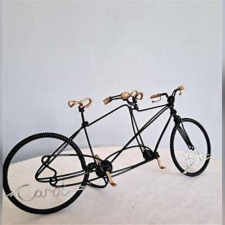 Black miniature tandem sculpture made from galvanised steel and hand painted black with gold handles, seat and pedals. Made as a wedding cake topper and personalised with two names written in wire and set into the front and back wheel of the bicycle.