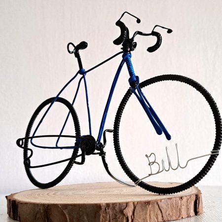 Handmade, blue colour, curved handle bars wire bicycle sculpture. Approximately 9cm long 4.5cm high, personalised with a name written in wire and set into the front wheel.