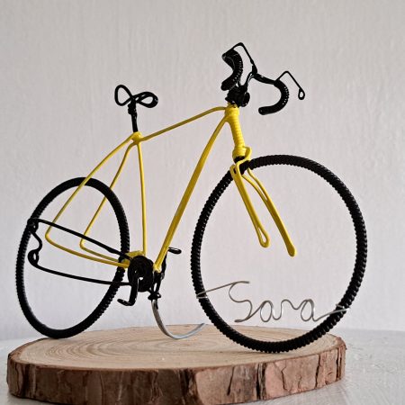 Handmade, yellow colour, curved handle bars wire bicycle sculpture. Approximately 9cm long 4.5cm high, personalised with a name written in wire and set into the front wheel.