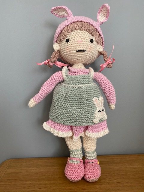 Handmade Crochet Lily the Doll, with a Pink dress and green apron.