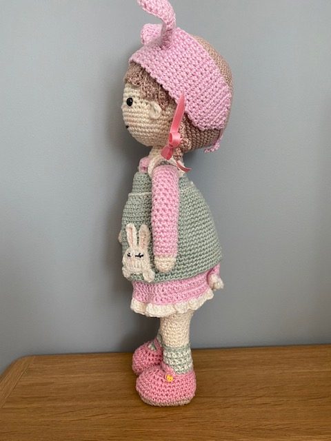 Handmade Crochet Lily the Doll, with a Pink dress and green apron.