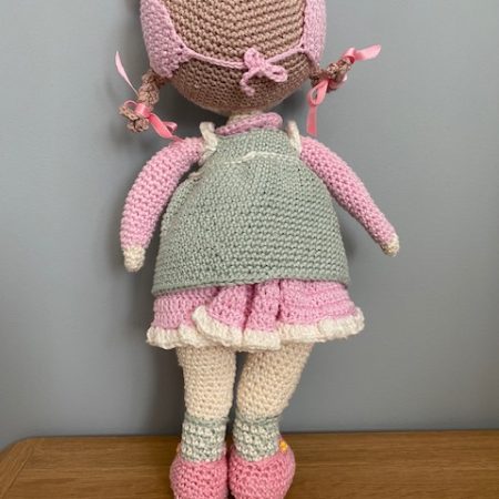 Handmade Crochet Lily the Doll, with a Pink dress and green apron.