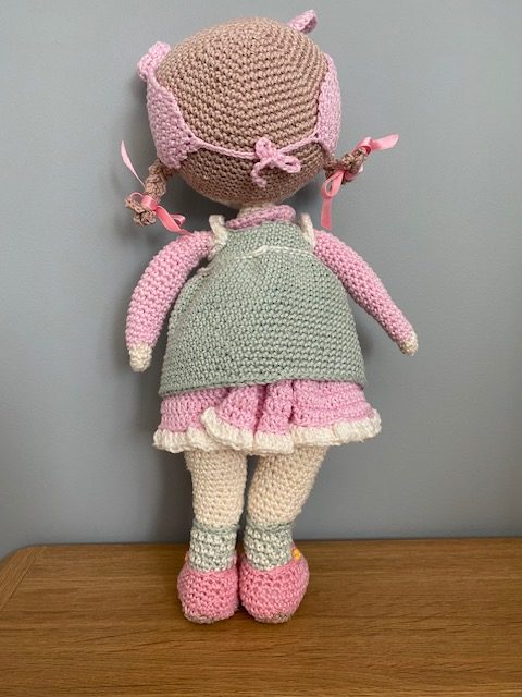 Handmade Crochet Lily the Doll, with a Pink dress and green apron.