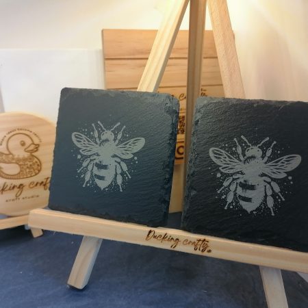 A pair of Hand made black slate coasters etched with a bumble bee