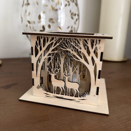 Natural plywood lantern with layered woodland trees and a stag and doe scene, standing on a square wooden base.