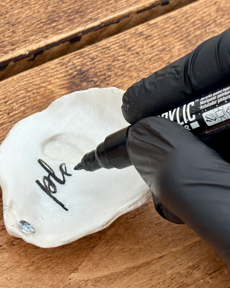 hand-lettering a message onto one of SHUCKED’s prepared oyster shells
