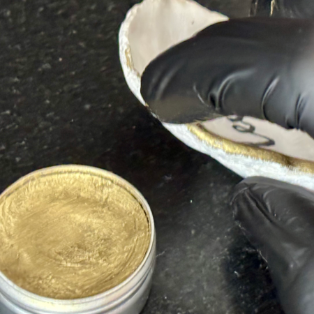 applying optional rich gold metallic gilding wax to the rim of a SHUCKED oyster shell according to the customer’s preferences