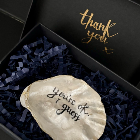 a SHUCKED shell lying in its gift box with a thank you message on the underside of the lid